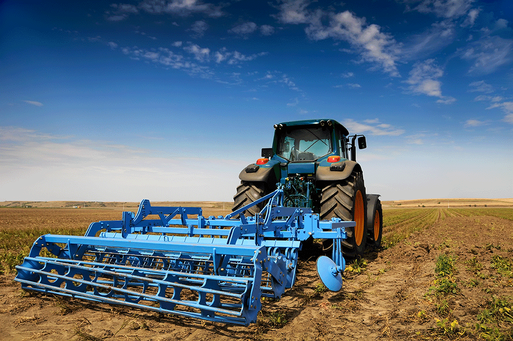 Tractor with blue equipment trailer parked on a field under a clear blue sky – AI-generated image
