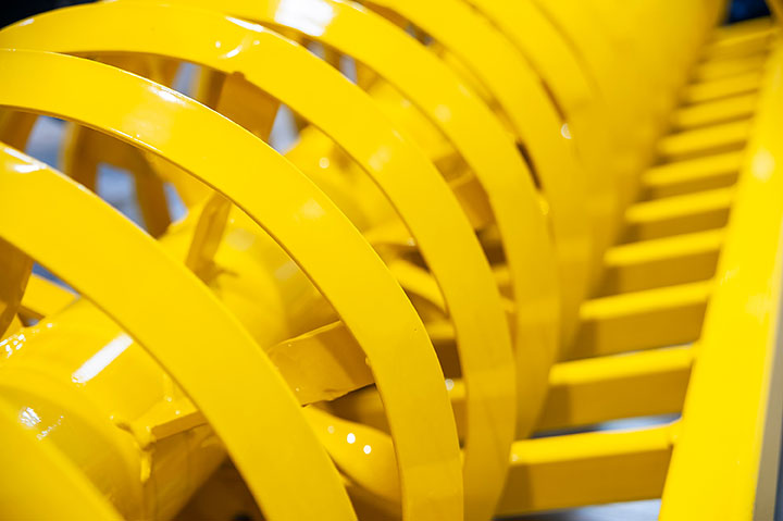 Bright yellow metal rings and bars forming part of an industrial machine or equipment.