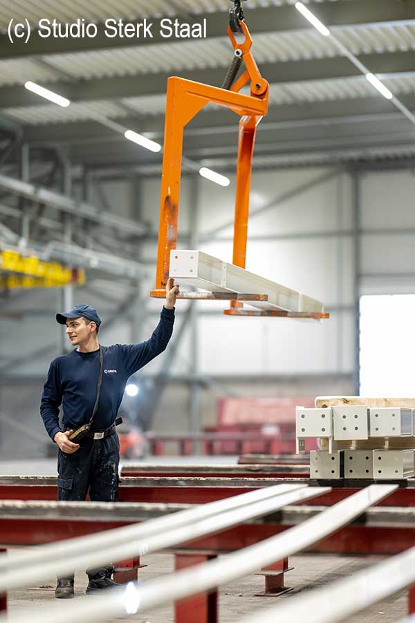 Industrial lifting of coated steel components using an overhead crane system inside Ansova’s modern powder‑coating facility.