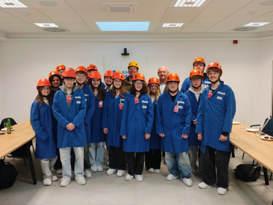 Career-Days_Austria A group of children in blue coats and orange helmets are standing together in a classroom