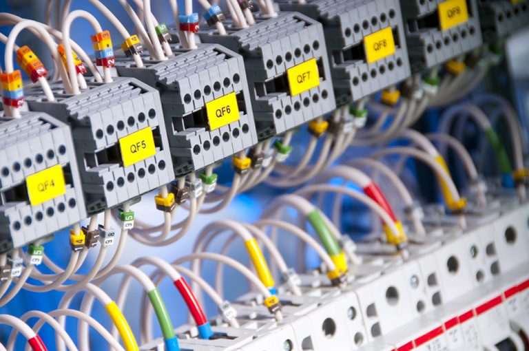 Coatings_for_electric_circuits “Close-up view of labeled electrical circuit breakers and colored wiring in a control panel, symbolizing industrial electronics and precision engineering.
