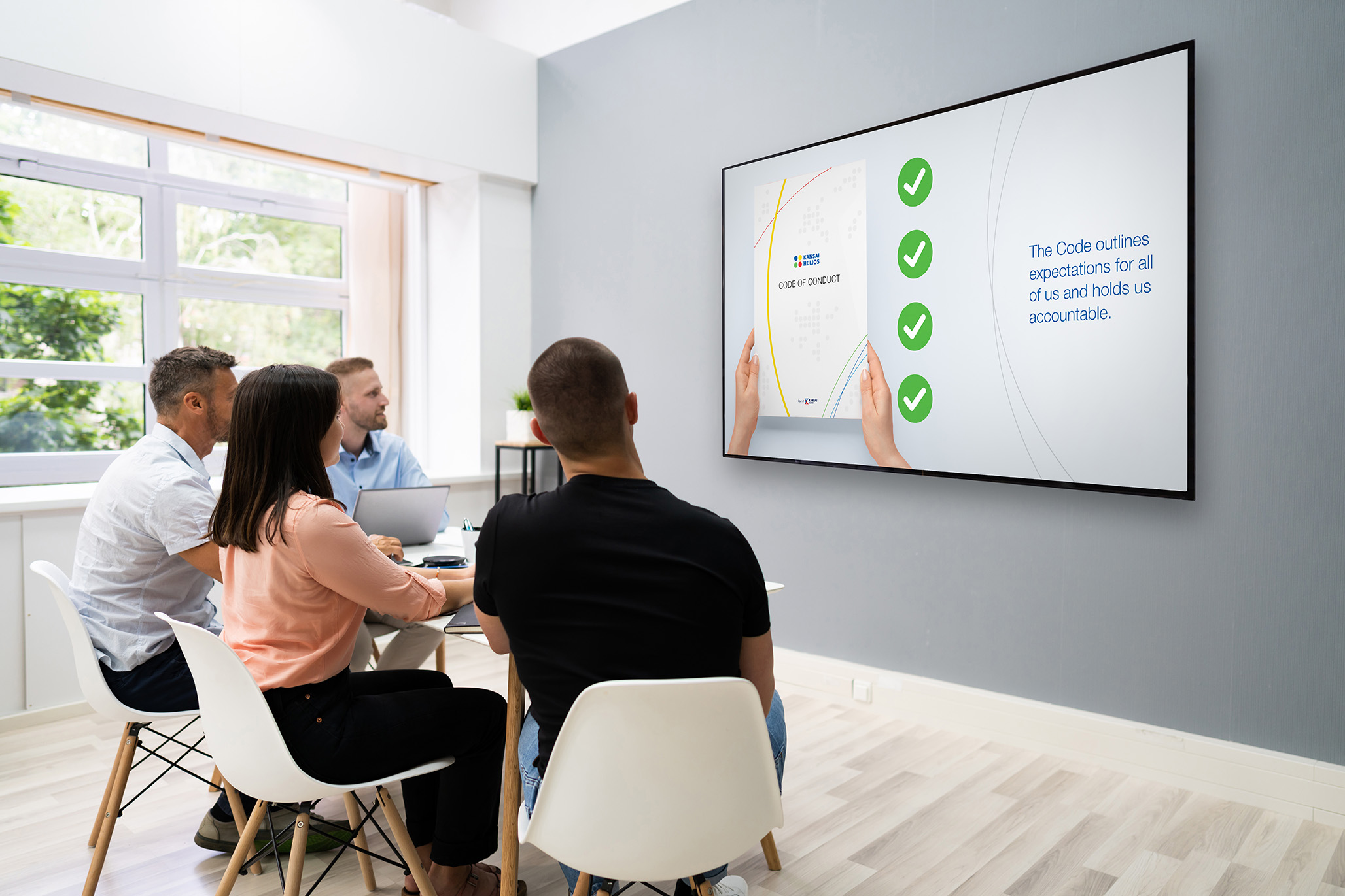 Group in meeting room viewing KANSAI HELIOS “Code of Conduct” slide.