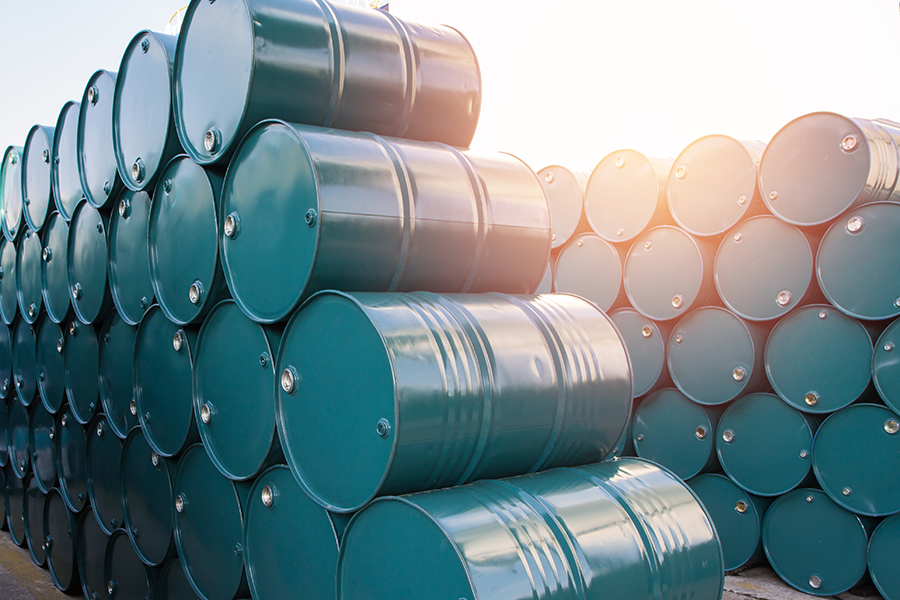 Drums_659753773 Stacks of green metal barrels arranged in rows outdoors.