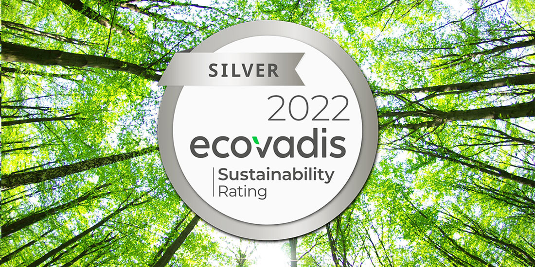 Circular silver badge with "SILVER" on a ribbon and "2022 ecovadis Sustainability Rating" below, set against a background of sunlit green tree canopy.