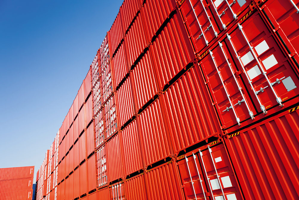 Helios-One-container Large stack of red cargo containers against a clear blue sky, symbolizing global shipping and logistics
