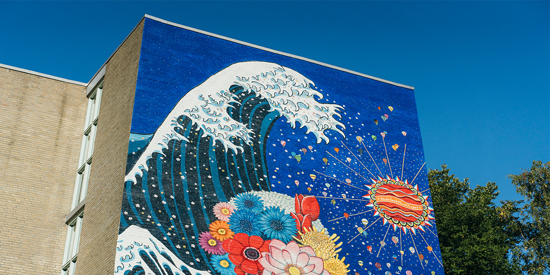 artistically painted facade showing a big water wave, flowers and a face