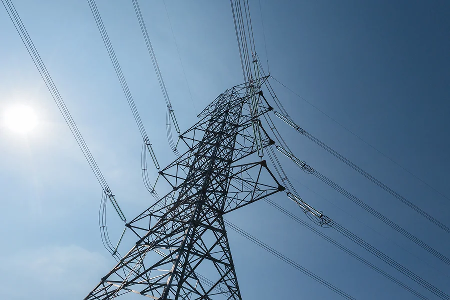 Pylon Close-up silhouette of an electricity pylon with high-voltage power lines against a clear blue sky