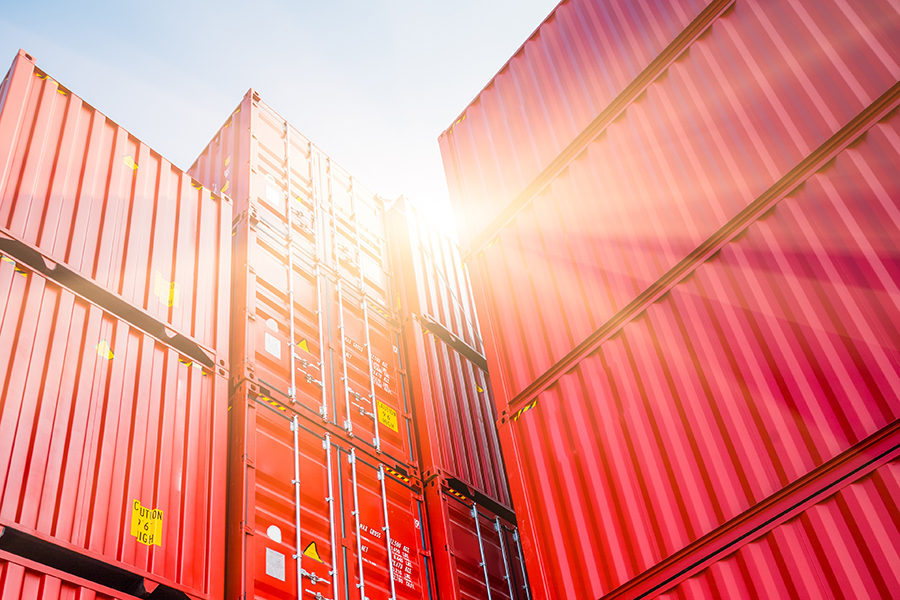 containers_stock_279234275 Stacked red industrial containers outdoors in bright sunlight
