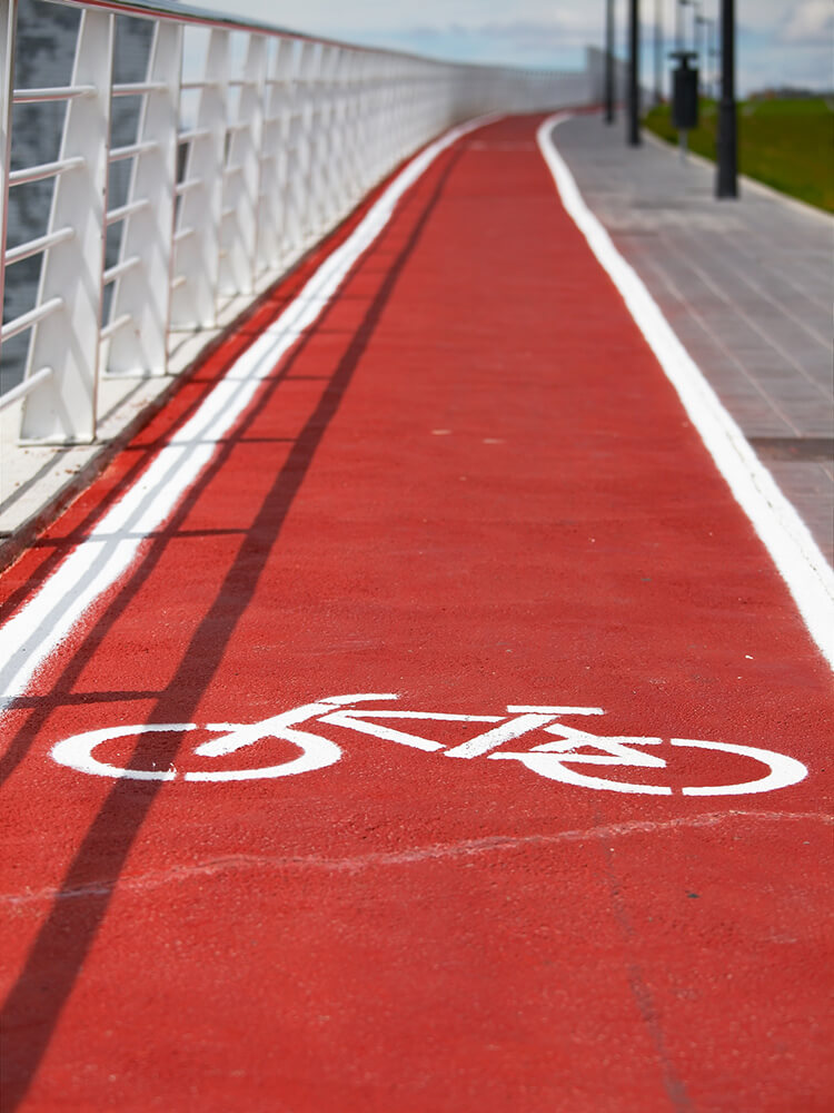 Red urban bicycle lane with white bike symbol and safety markings for sustainable city transportation