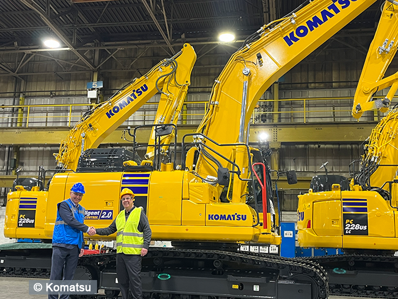 two men standing in front of yellow cranes
