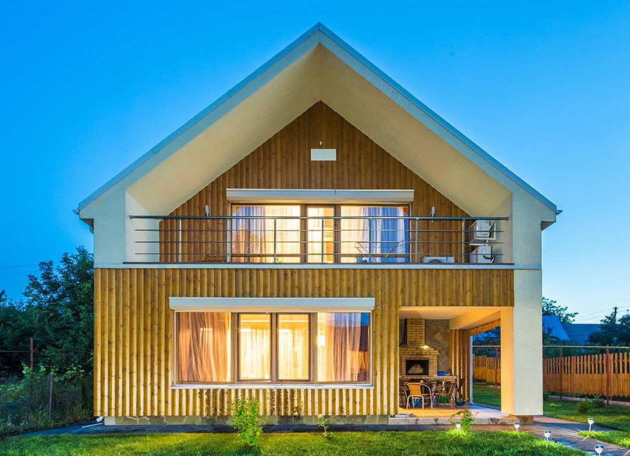 A modern, eco-friendly house with wood and plaster exterior, large windows, and surrounded by greenery - designed for natural light and sustainable living.