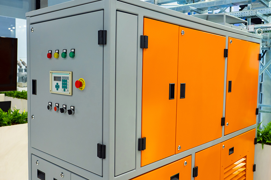 enclosure_shutterstock_1536582731 An industrial control cabinet with gray and orange panels, featuring buttons, switches, and a digital display on the front.