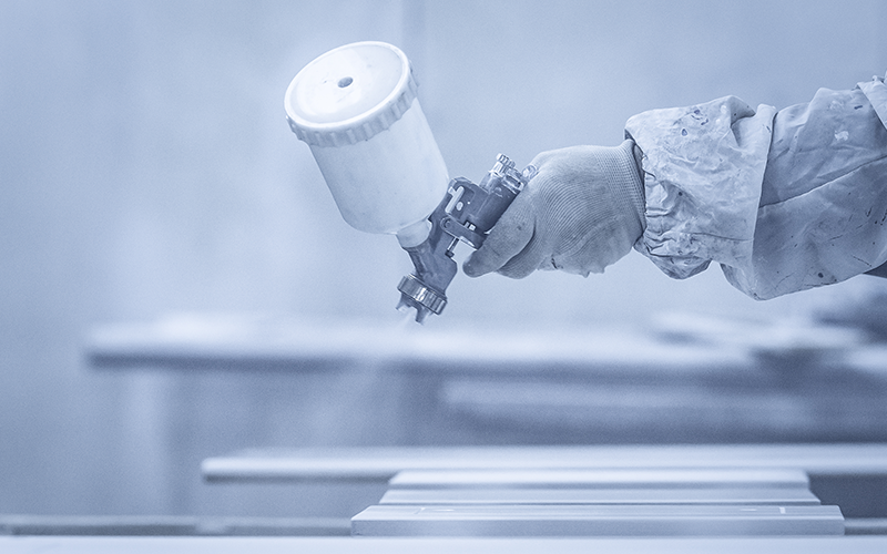 powder-application hand of a coater that is spray painting white powder coating on top of a metal sheet