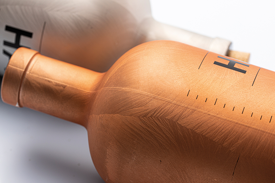 senoglass_fire-efrfect_ED4A0854 closeup of two premium bottles with a special coating effect (feather) in gold/copper and silver