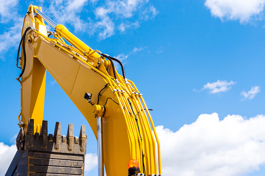 yellow excavator arm against a clear blue sky