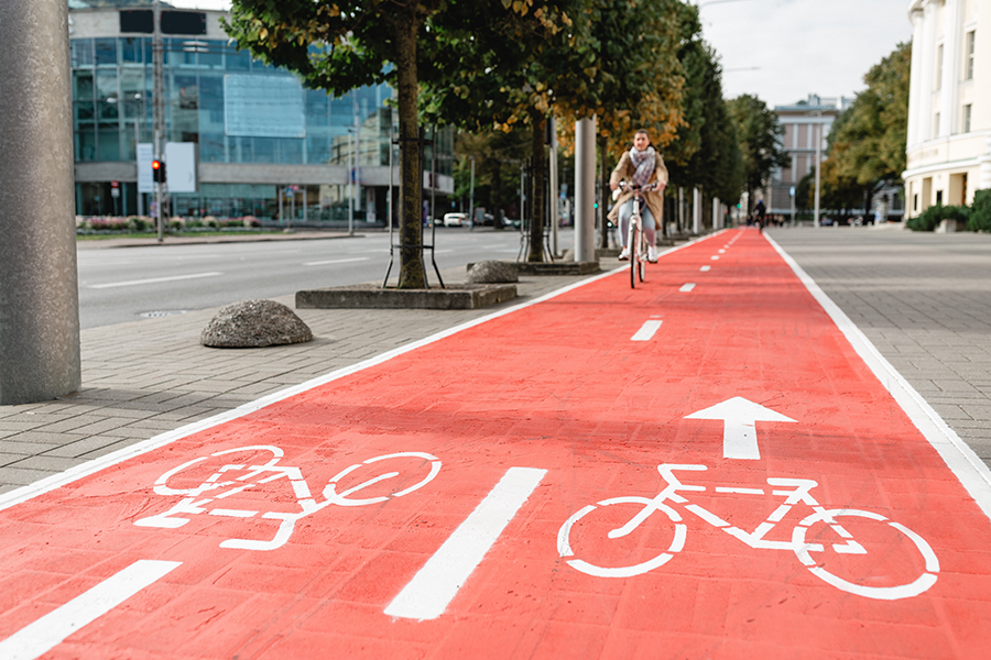 Urban scene: A woman riding a bicycle on a red bike path.