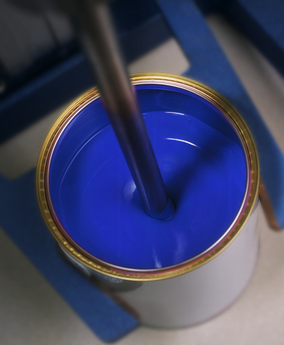 Blue,Paint,In,Tin,On,Mixing,Machine Blue liquid paint in an open can with industrial stirring equipment.